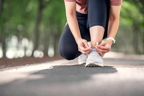 閉じる ランニングシューズランナーの女性は 森林公園で夏のランニングのためのレースを結びます ジョギングの女の子運動動機健康とフィットネス運動 コピースペース — ストック写真