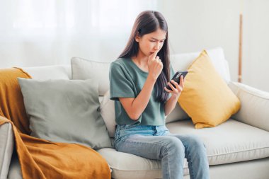 Akıllı telefon ekranına bakan endişeli genç bir kadın, kötü haber, spam veya dolandırıcılık mesajlarından memnun değil. Kötü ruh hali yaşam tarzı konsepti.
