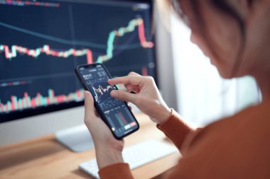 Yakın plan - Kadın akıllı telefon, kripto para birimi gelecekteki fiyat öngörüsünde Bitcoin fiyat tablosunu kontrol ediyor.