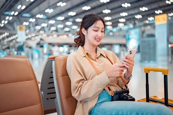 Happy asian tourist woman using mobile with suitcase traveling between waits for flight in Airport Terminal, Browse Internet, flight check in, Tourist journey trip concept