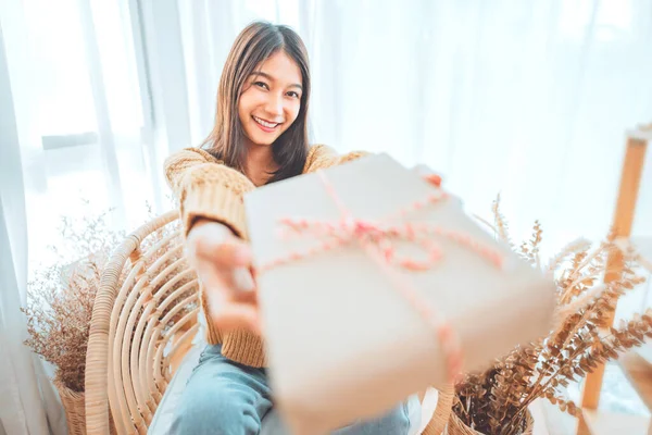 Giving a gift, Happy young asian woman giving handmade present wrapped paper. Christmas time. New Year\'s Eve and gift giving