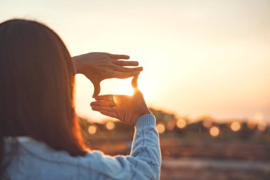 Yeni yıl planlama ve vizyon konsepti, kadın eli kapanışı, gün batımında çerçeve hareketi, gün doğumunu yakalayan kadın. Boşluğu kopyala.