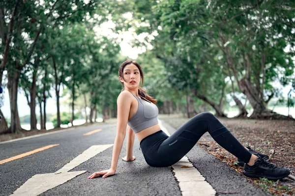 通りに座って 健康的なライフスタイルやスポーツの概念に囲まれた公園でジョギングした後 休んで疲れたアジアの女性 — ストック写真