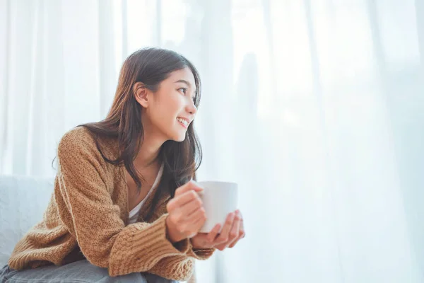 Gledelig Asiatisk Kvinne Som Slapper Mens Hun Drikker Varm Kaffe stockfoto