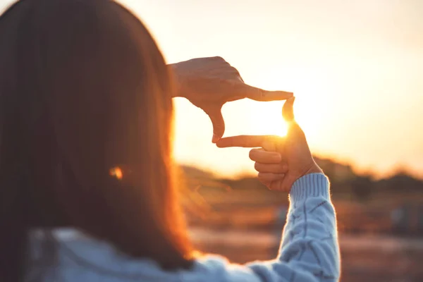 Woman hands making frame gesture with sunset, Female capturing the sunrise.