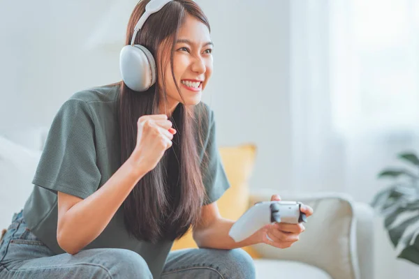 兴奋的女玩家头戴耳机 在客厅里玩电脑游戏 在家活动 图库图片