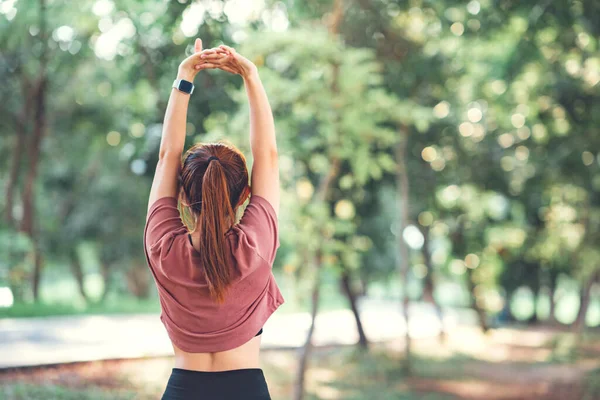 健康的女人做伸展运动 伸展胳膊 女人在跑动或在公园外锻炼前伸展热身 图库照片