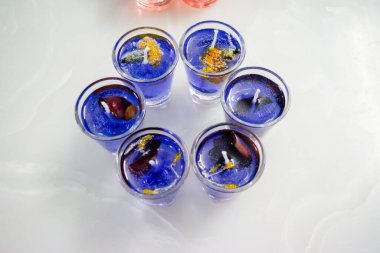Beyaz arka planda izole edilmiş cam jel mum. Renkli jel mumlar. Camda mum ve bir sürü renkli mum..