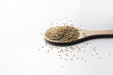 Beyaz yüzeyinde tohumlar olan tahta kaşıkta kinoa. Boşluğu kopyala