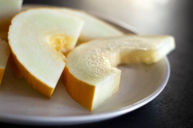 Beyaz bir tabakta dilimlenmiş sarı kavunu kapat.