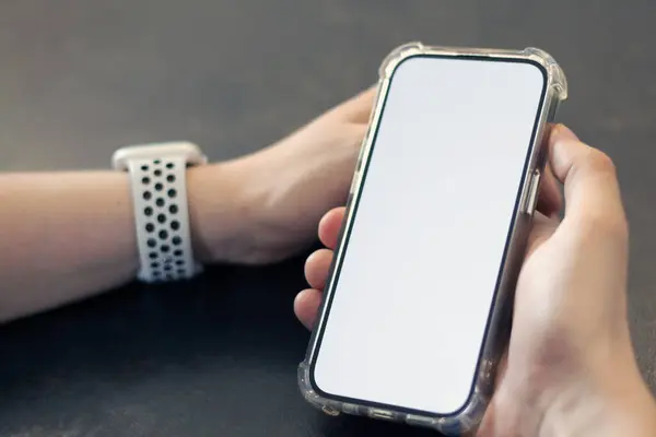 Genç adam cep telefonunu dokunmatik beyaz ekran modelleme şablonu kullanarak tutuyor