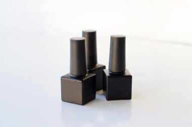 Üç kare lüks mat. Beyaz arka planda siyah oje şişeleri.