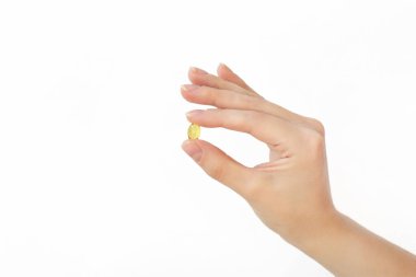 Beyaz arka planda altın yağ hapı kapsülü, ilacınızı veya vitaminlerinizi alıyor.