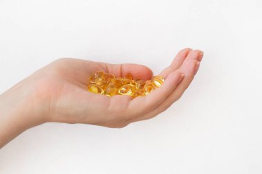 Tedavi konsepti. Kadının elleri beyaz arka planda altın vitamin kapsülleriyle dolu. Eczane ilacı manzarası. Balık yağı, E vitamini, Omega 3 hapları. Eczacılık ilaçları var. Vitamin takviyesi. Kadın ellerinde bir yığın hap.