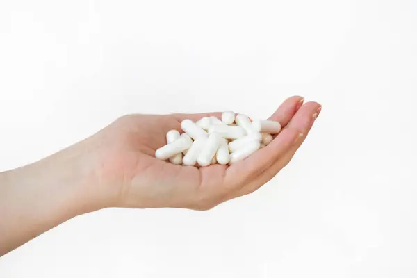 Tedavi konsepti. Beyaz arka planda beyaz ilaç dolu bir kadının elleri. Eczane ilacının en iyi görüntüsü. Sağlık sigortası konsepti. Eczacılık ilaçları var. Vitamin takviyesi. Kadın ellerinde bir yığın hap.