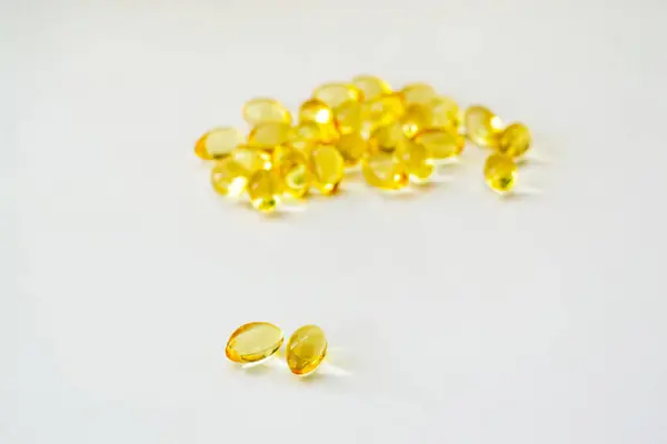 Beyaz arka planda morina yağı vitamini ve yumuşak jel kapsülleri