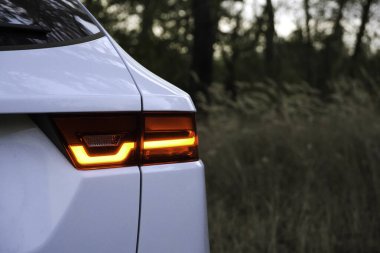 Ormandaki spor beyaz arabanın arka stop LED ışığı, Supercar 'ın stop lambası. Modern fren lambalı spor araba kuyruğu.