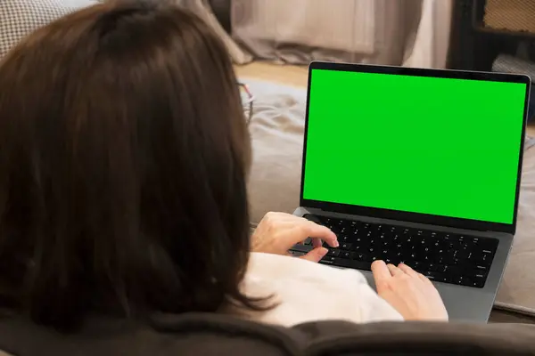 Kadın rahat bir oturma odasındaki kanepede dizüstü bilgisayar kullanıyor. Evden çalış, dizüstü bilgisayar modeli.