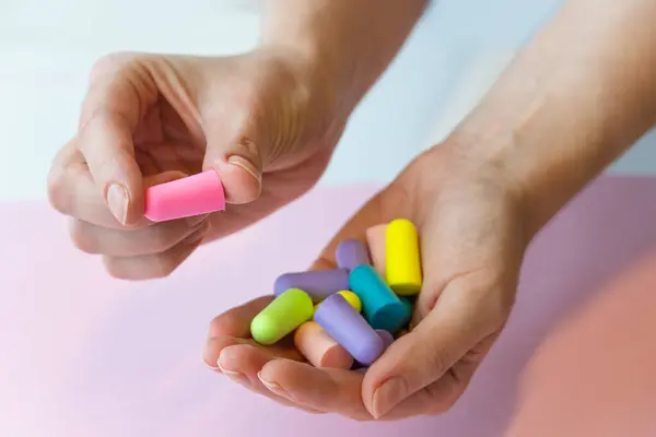 Bir grup renkli kulak tıkaçları gürültü azaltma uyku horozu sessiz kavanoz, kulak tıkacı tutan kadınlar.