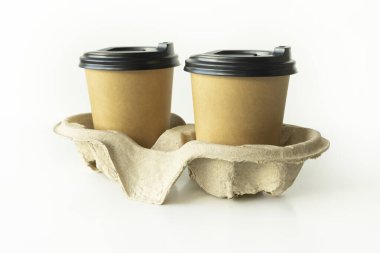 Plastik kapaklı kahve fincanları ve karton tutacaklı beyaz arka planda, çevre dostu, biyolojik olarak çözünebilir.