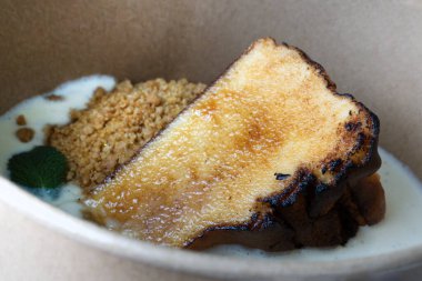 Karton kasede yanmış bir dilim Bask peynirli kek, yiyecek teslimatı, geleneksel tatlı.