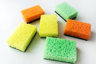 Beyaz arka planda renkli köpük süngerleri. Mutfak süngeri. Temizlik konsepti, temizlik hizmeti. Bulaşık deterjanı ve temiz ve kirli tabaklar. Mesaj için yer, kopyala. Bulaşıkları yıka.