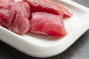 Siyah masadaki beyaz dikdörtgen tabakta dilimlenmiş ton balığı, yakın planda balık bifteği.