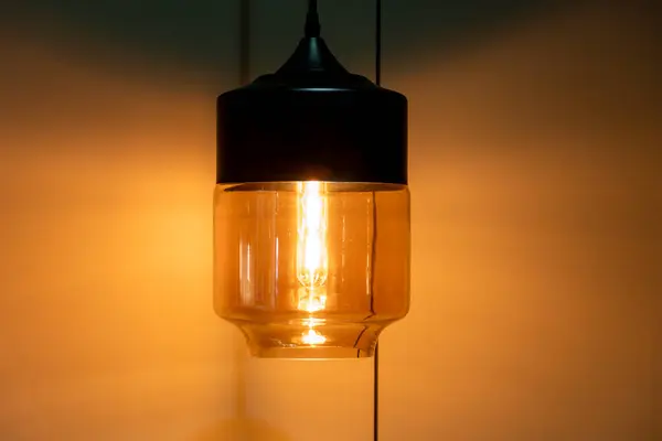 Aydınlatılmış siyah altın bir duvar lambası. Yaklaş, uzayda sıcak, davetkar bir parıltı bırak.,