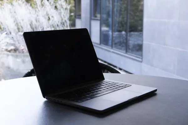 Yuvarlak bir masada açık arka planı olan bir bilgisayar. Model tasarımı, iş, uzak çalışma veya modern çalışma alanı temaları için.