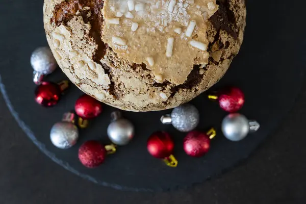 Panettone - geleneksel Noel pastası üst görünümü siyah arkaplan renkli toplar, lezzetli paskalya pastası