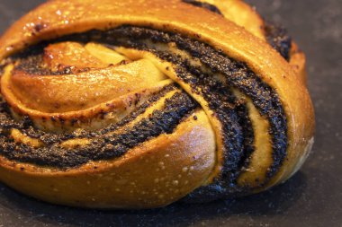 Yeni pişmiş haşhaşlı çöreğe yakın plan altın kabuklu ve zengin dolgulu, geleneksel tatlı hamur işi.