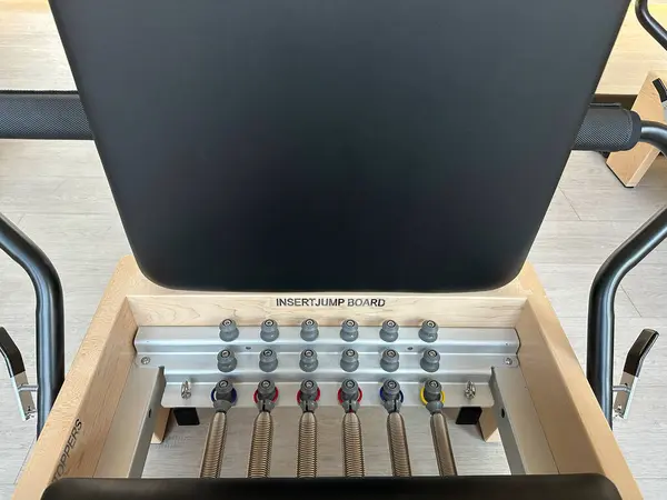 Bir fitness stüdyosunda yaylı ve atlama tahtası takılı bir pilates reformatör makinesinin yakın çekimi..