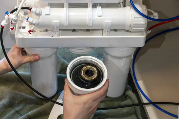 Rutin yenileme sırasında arıtma sisteminden kaldırılan kirli su filtresi kartuşunun görünümünü kapat.