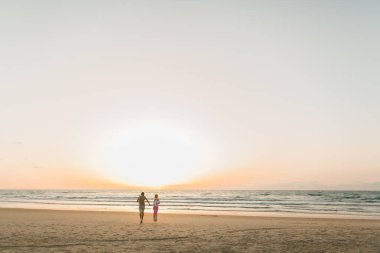Genç çift sahilde günbatımının tadını çıkarıyor..