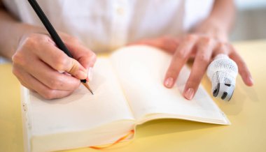 Females hand making notes with pencils and empty notebooks in their room.
