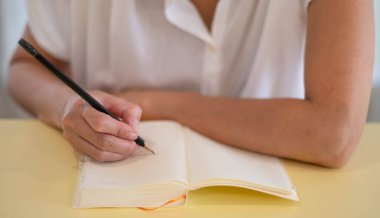 Females hand making notes with pencils and empty notebooks in their room.
