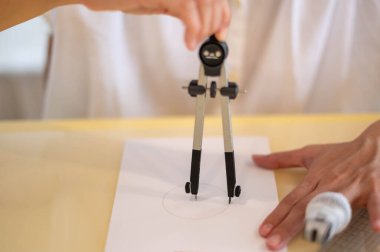 Female hand using a measured circle preparing to draw and sketch on the empty white paper.