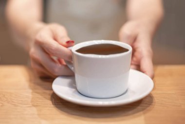 Kadın eli, kahve dükkanındaki müşteriye bir fincan kahve ikram eder..