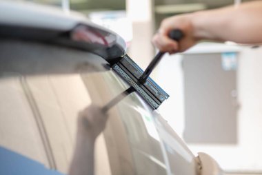 Olgun erkek işçi, arabanın ön camını süngerle siliyor..