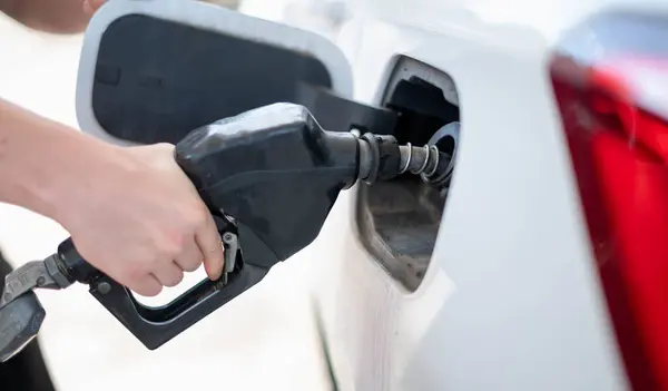 Female worker hand holding nozzle fuel fill oil into car tank at pump gas station, For the concept transportation power business technology concept