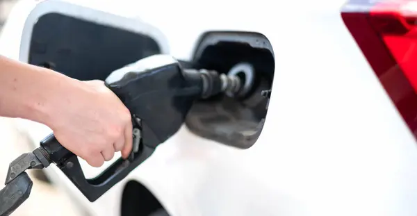 Female worker hand holding nozzle fuel fill oil into car tank at pump gas station, For the concept transportation power business technology concept