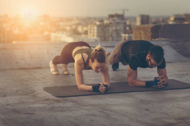 Çatıdaki terasta egzersiz yapan bir çift.
