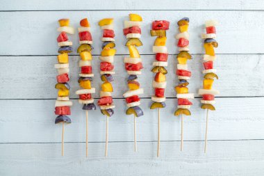 Barbekü çubuklarında servis edilen soğuk renkli karışık meyve salatasının en üst görüntüsü yaz tatlısıdır.