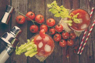 Votka, limon ve domates suyu, acı sos ve kereviz yapraklarıyla süslenmiş buz küpleriyle dolu bir Bloody Mary kokteyli. Gözlüklere odaklan.