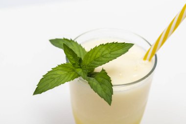 Nane yapraklarıyla süslenmiş, beyaz arka planda izole edilmiş bir bardak soğuk kavun suyu.