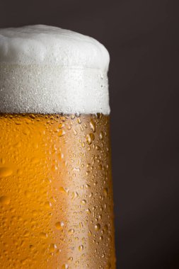 Köpüklü ıslak bir bardak soğuk light biranın ayrıntıları. Seçici odak