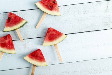 Açık mavi ahşap arka planda izole edilmiş karpuz buzlu dondurmanın masa üstü görüntüsü.