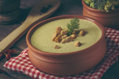 Yüksek açılı taze kremalı brokoli çorbası kıtır ekmek ve taze dereotu yapraklarıyla süslenmiş. Dereotu yaprakları ve kızarmış ekmeklere odaklan.