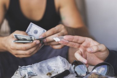 Uyuşturucu satıcısı bir uyuşturucu bağımlısına ecstasy hapı satıyor.