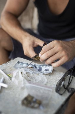 Kenevir tomurcuklarını makasla öğüten erkek ellerinin detayları. Tomurcukların öğütülmesine odaklan